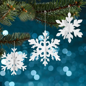 Detailed view of white 3D snowflake hanging ornaments on green pine branches