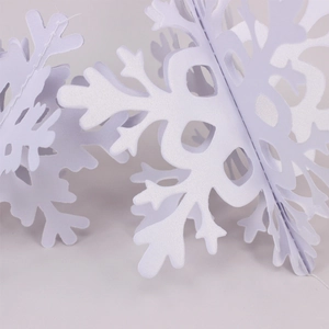 Detail of 3D white paper snowflake hanging ornament showing geometric folding and stitching