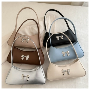 Flat lay of multiple stylish armpit bags with metal bow detail in various colors