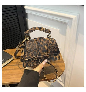 Detail of leopard print handbag with golden hardware and textured faux leather finish