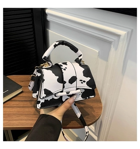 Detail of cow print mini crossbody bag with gold hardware and chunky top handle