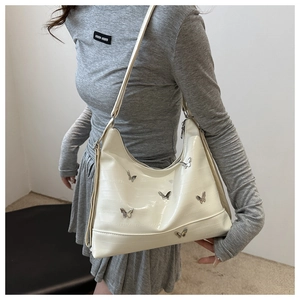 Detail of white crocodile texture underarm bag with silver metal butterfly ornaments