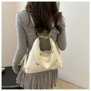 Detail of cream PU leather backpack featuring decorative silver metal butterfly buckles