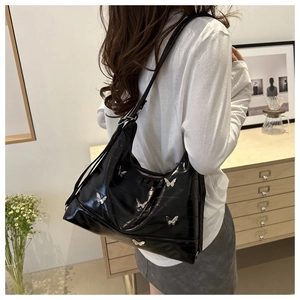 Close-up of black glossy hobo bag with silver butterfly charms and quilted details