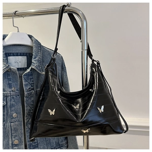 Detail of black glossy tote bag with silver butterfly charms and pleated texture finish