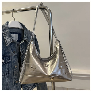 Detail view of silver quilted hobo bag with metallic butterfly accents and strap