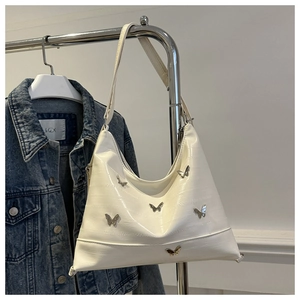 Detail of white crocodile pattern shoulder bag with silver butterfly metal charms