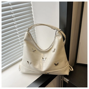 Detail of cream hobo bag featuring silver butterfly studs and croc-embossed texture
