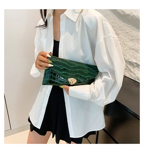 Détail d'une pochette enveloppe vert foncé effet crocodile avec fermoir doré