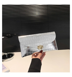 Détail de pochette enveloppe argentée à motif crocodile et fermoir en métal doré