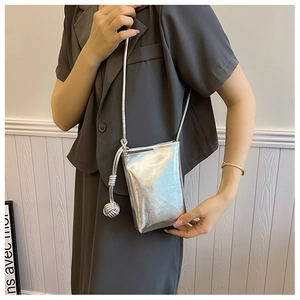 Close-up of metallic silver mini crossbody phone bag with round woven pendant detail