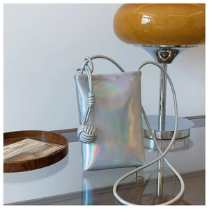 Detailed macro view of holographic silver mini crossbody phone bag with woven ball charm