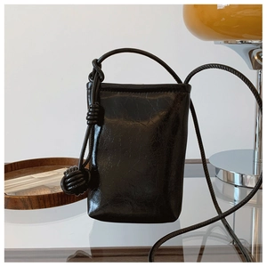 Detail of glossy black pleated leather texture and stylish knotted cord shoulder strap
