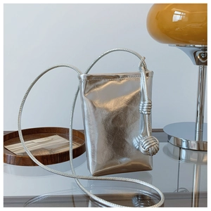 Detailed view of silver metallic leather crossbody bag with distinctive knot strap detail