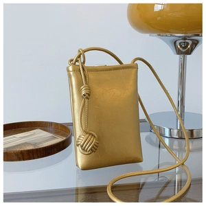 Detail of golden metallic textured phone crossbody bag with decorative oversized knot