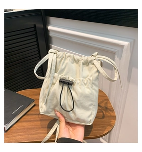 Détail d'un sac seau en nylon crème avec cordon de serrage et boucle réglable noire