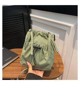 Détail du sac seau en nylon vert sauge avec cordon de serrage et poche avant texturée