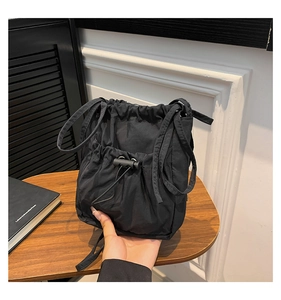 Détail du sac seau noir en nylon avec cordon de serrage, doubles poignées et texture lisse