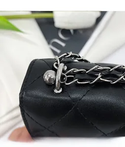 Dettaglio catena argento con fibbia a sfera regolabile su borsa in pelle nera trapuntata