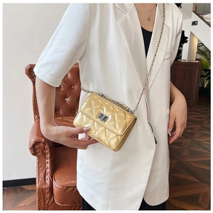 Dettaglio borsa a tracolla trapuntata dorata con catena su un elegante blazer bianco