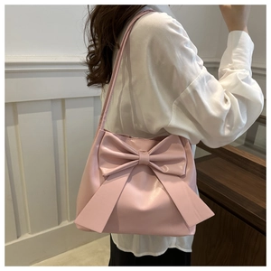 Detail of pink leather bucket bag featuring a large decorative bow on the side for women