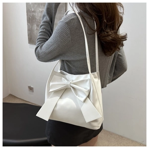 Close-up of white tote bag featuring a large decorative bow and smooth leather texture