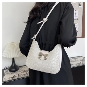 Detail of white woven texture shoulder bag with silver bow buckle and knotted strap