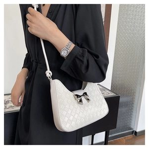 Detail of white woven hobo bag with black bow metal clasp worn by a model