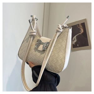 Detail of white woven leather shoulder bag with a silver bow-shaped metal clasp