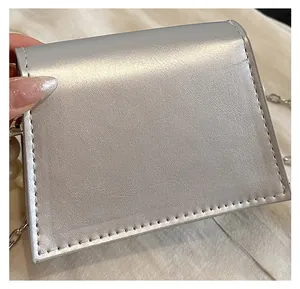 Detail of silver mini pouch with pearl bead chain strap and glossy metallic leather texture
