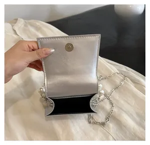 Detailed interior of silver mini bag showing magnetic closure and black fabric lining