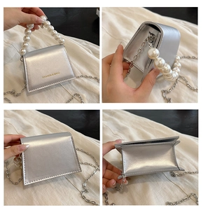 Detail view of silver mini crossbody bag with pearl handle and metal chain strap