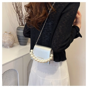 Silver chain crossbody bag featuring elegant pearl top handle and metallic leather finish