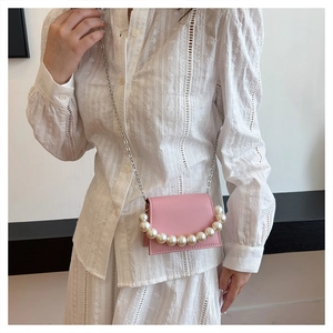 Detailed view of pink mini bag featuring large pearl handle and silver chain strap