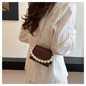 Detail of a brown mini bag featuring large pearls and a silver chain strap