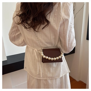 Detail of dark brown mini bag with large pearl inlay and silver chain strap