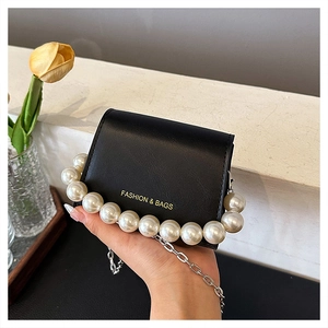 Detail of black mini crossbody bag with large pearl trim and gold lettering