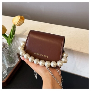 Detail of dark brown leather mini bag with pearl trim and gold fashion lettering