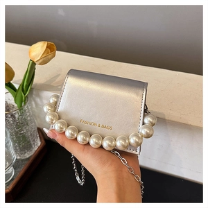 Chic silver mini crossbody bag with pearl handle and metal chain held in hand