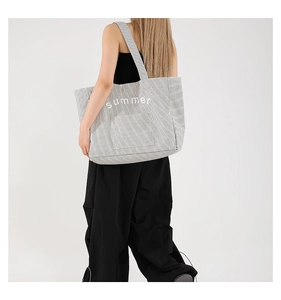 Detail of a large black and white striped canvas tote bag with summer print and outer pocket