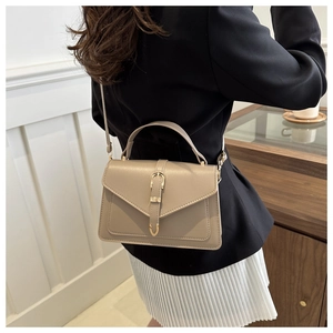 Detail view of khaki structured handbag with gold metallic buckle on a model back