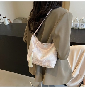Close-up of pink jacquard embroidery bucket bag with elegant white tassel detail