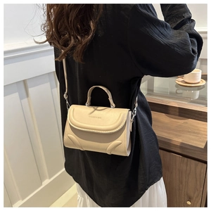 Detail einer beigen Lederumhängetasche mit FASHION & BAG Prägung und Silberringen