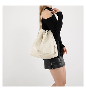 Model wearing a creamy white large tote bag with luxury patchwork design and drawstring closure