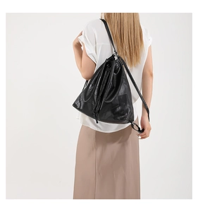 Detailed side view of black drawstring tote bag with shiny leather texture and thin straps