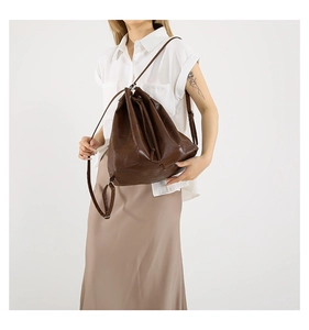 Detail of dark brown drawstring bucket bag featuring high-quality leather texture and strap