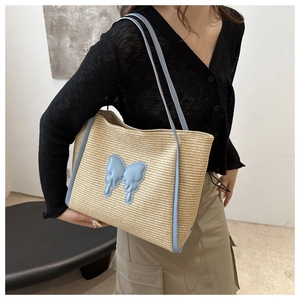 Detail of blue leather butterfly patch and woven straw texture on large summer tote bag