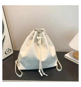 Detailed view of white quilted drawstring bucket bag with elegant paneled leather texture