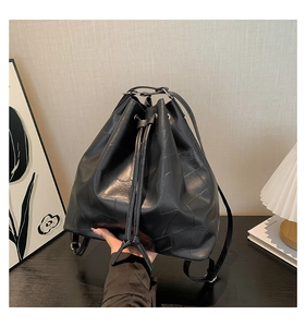 Detail of black faux leather bucket bag featuring unique geometric stitching and drawstring