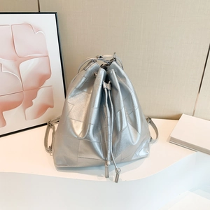 Silver metallic bucket bag with geometric stitching and drawstring in a modern setting